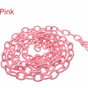 May include: Pink fabric chain with oval links. The chain is coiled into a circle.