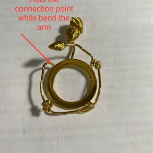Puede incluir: Porta anillos de metal dorado con un dise&ntilde;o floral decorativo. El porta anillos tiene una base circular y un tallo delicado con hojas y flores.