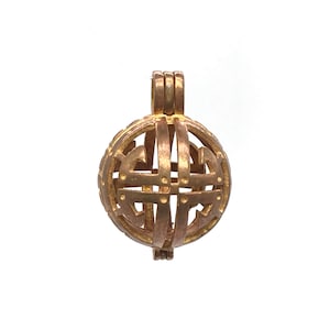 Może przedstawiać: Złoty metalowy wisiorek w kształcie klatki z delikatnym, skomplikowanym wzorem. Klatka jest otwarta z jednej strony i ma pętlę na górze do zawieszenia.