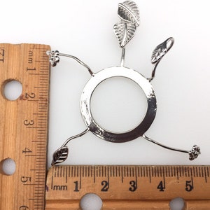 Puede incluir: Porta-pantallas de l&aacute;mpara de metal plateado con tres brazos en forma de hoja y una base redonda. El porta-pantallas mide aproximadamente 10 cm de di&aacute;metro.