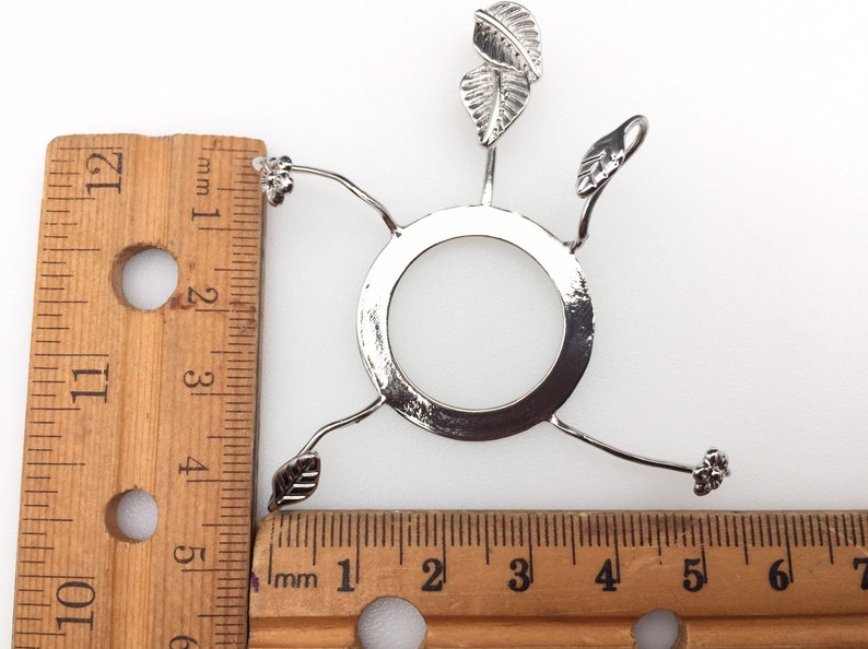 Puede incluir: Porta-pantallas de l&aacute;mpara de metal plateado con tres brazos en forma de hoja y una base redonda. El porta-pantallas mide aproximadamente 10 cm de di&aacute;metro.