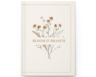May include: A cream-colored journal with a floral design and the text "BLOOM & BRANCH." The cover features a bouquet of brown and pink flowers with green stems. A thin, gold-colored border frames the cover.