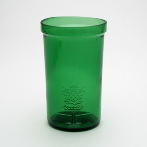 May include: A green glass drinking glass with a raised design of a thistle on the front.