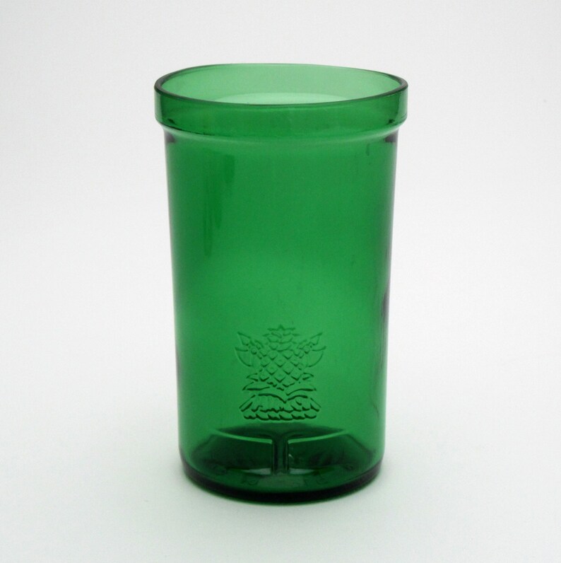 May include: A green glass drinking glass with a raised design of a thistle on the front.