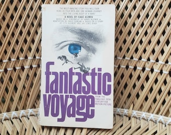 May include: A vintage paperback book cover with a purple title "Fantastic Voyage" and a close-up image of a blue eye with divers swimming in front of it. The text on the cover reads "The most amazing story you will ever read. Four men and one woman journey into the living body of a man!" and "From the famous 20th Century Fox motion picture."