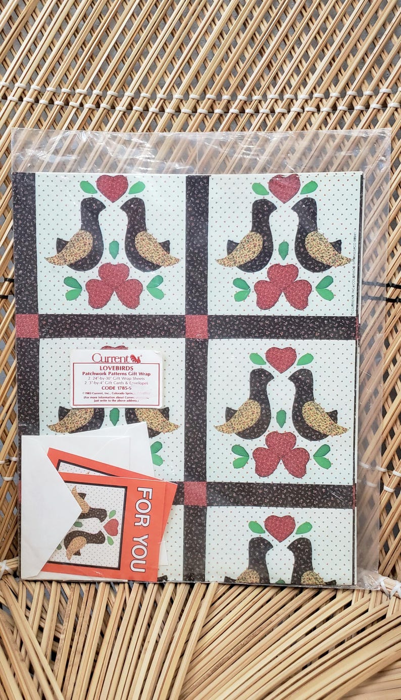 Puede incluir: Un paquete de papel de regalo de estilo patchwork con un patr&oacute;n de p&aacute;jaros negros y marrones con corazones rojos y hojas verdes sobre un fondo blanco con lunares negros. El paquete incluye dos etiquetas de regalo que dicen "Para Ti". El paquete est&aacute; etiquetado "Current's Lovebirds Patchwork Patterns Gift Wrap 2-7/8' x 11' Rolls 2 Gift Cards & Envelopes CODE 1785"