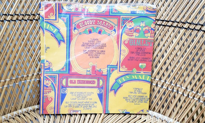 Puede incluir: Un papel de envolver vintage colorido para recetas de c&oacute;cteles con un dise&ntilde;o amarillo, rojo y azul. El papel presenta recetas de c&oacute;cteles Bloody Mary, Gimlet, Old Fashioned y Tom Collins.