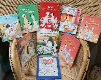 May include: A collection of ten children's books featuring the Disney characters from the movie 101 Dalmatians. The books are arranged in a semi-circle on a wicker chair. The books have colorful covers with illustrations of the Dalmatian dogs.