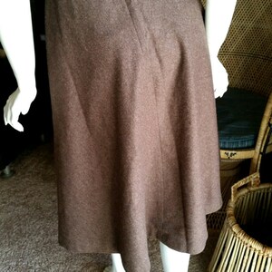 May include: A brown wool midi skirt with a simple design and a button closure at the back.