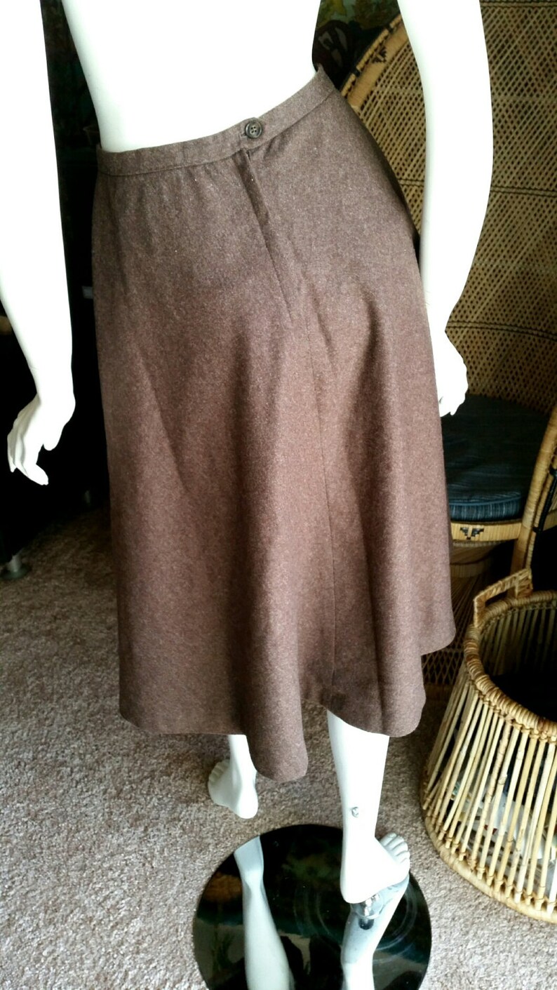 May include: A brown wool midi skirt with a simple design and a button closure at the back.