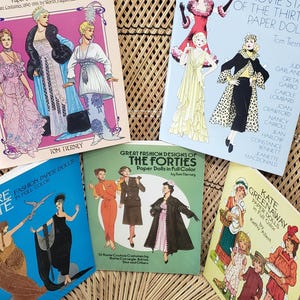 Puede incluir: Una colecci&oacute;n de libros de mu&ntilde;ecas de papel vintage con dise&ntilde;os de moda de varias &eacute;pocas. Las portadas muestran ilustraciones de figuras elegantes con atuendos coloridos, con t&iacute;tulos como "Great Fashion Designs" y "Glamorous Movie Stars".