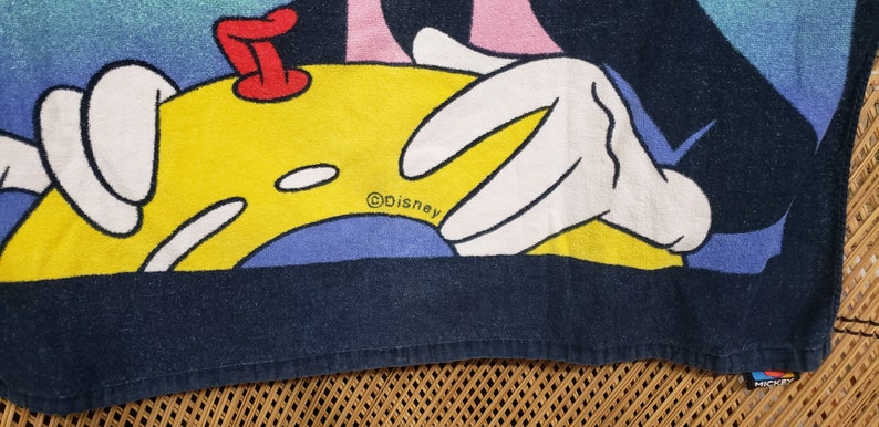 May include: A blue and yellow beach towel featuring a cartoon image of Mickey Mouse with the text "&copy;Disney" and "Mickey".