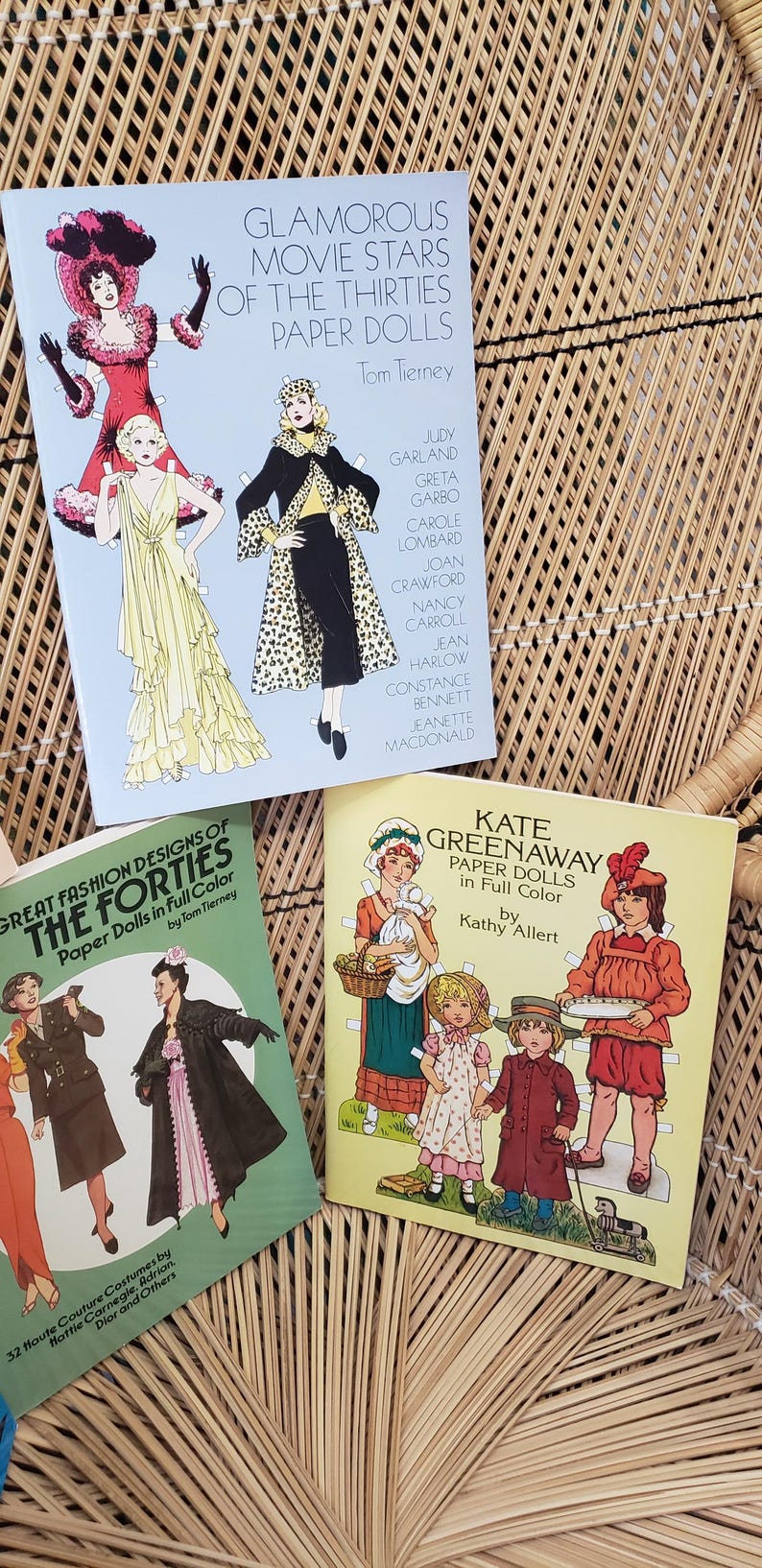 Puede incluir: Tres libros de mu&ntilde;ecas de papel vintage. Los t&iacute;tulos incluyen "Glamorous Movie Stars of the Thirties", "Great Fashion Designs of the Forties" y "Kate Greenaway Paper Dolls". Los libros presentan ilustraciones de moda y estrellas de cine.