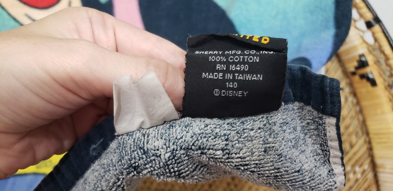 May include: A black tag with white text that reads "SHEART MFG. CO., INC. 100% COTTON RN 16490 MADE IN TAIWAN 140 DISNEY".