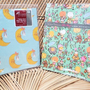 Puede incluir: Dos rollos de papel de regalo vintage. Un rollo presenta un fondo azul con un patr&oacute;n repetitivo de medias lunas amarillas con lazos rosas. El otro rollo presenta un fondo verde con un patr&oacute;n repetitivo de peque&ntilde;as figuras de dibujos animados en un entorno de jard&iacute;n. El texto en el papel de regalo dice "All Occasion Giftwrap".