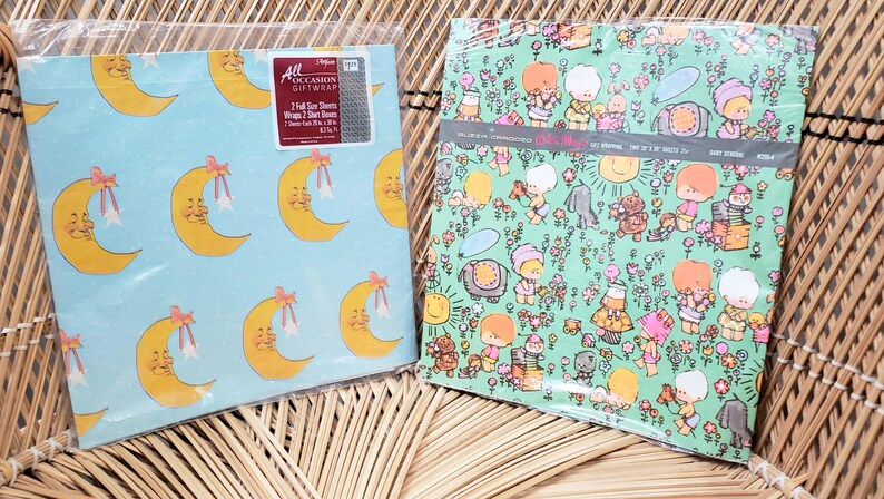 Puede incluir: Dos rollos de papel de regalo vintage. Un rollo presenta un fondo azul con un patr&oacute;n repetitivo de medias lunas amarillas con lazos rosas. El otro rollo presenta un fondo verde con un patr&oacute;n repetitivo de peque&ntilde;as figuras de dibujos animados en un entorno de jard&iacute;n. El texto en el papel de regalo dice "All Occasion Giftwrap".