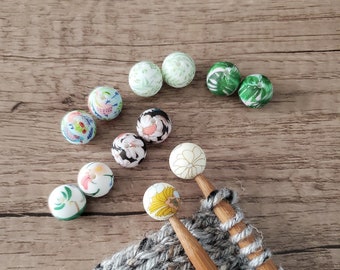 Könnte beinhalten: Nahaufnahme eines Strickprojekts mit Holzstricknadeln und bunten Perlen. Die Perlen sind mit Blumen- und Blattmotiven verziert. Die Stricknadeln liegen auf einem grauen Strickstoff mit dem Text "LEMON TREE SUPPLIES".