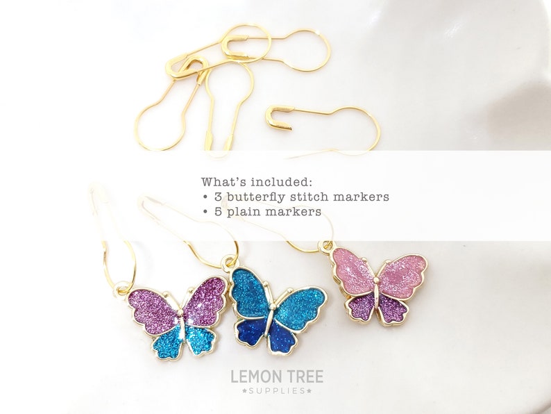 May include: A set of eight gold stitch markers, including three butterfly stitch markers with glitter accents in pink, blue, and purple, and five plain gold stitch markers. The text "What's included: 3 butterfly stitch markers 5 plain markers" is visible in the image.