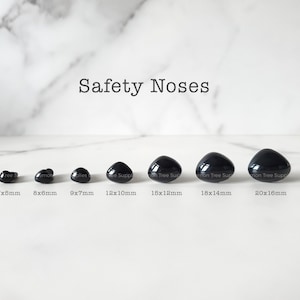 May include: A collection of black safety noses in various sizes, ranging from 7x5mm to 20x16mm, displayed on a white marble surface. The text "Safety Noses" is above the noses.