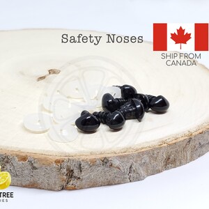 Puede incluir: Primer plano de narices de seguridad negras y arandelas blancas, dispuestas sobre una rodaja de madera. El texto "Safety Noses" es visible. Tambi&eacute;n est&aacute; la bandera canadiense.