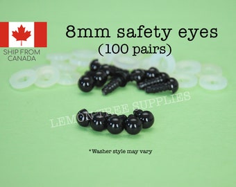 Puede incluir: Ojos de seguridad negros de 8 mm para manualidades, con 100 pares y arandelas blancas. El texto dice "8mm safety eyes (100 pairs)" sobre un fondo verde claro. También está escrito "Washer style may vary".