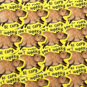 May include: A collection of yellow stickers featuring a brown capybara illustration. Each sticker has the text "BE CAPY DON'T WORRY" in black. The capybara is depicted in a running pose.