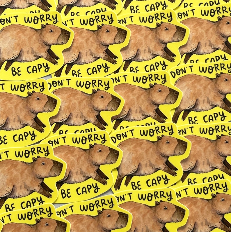 May include: A collection of yellow stickers featuring a brown capybara illustration. Each sticker has the text "BE CAPY DON'T WORRY" in black. The capybara is depicted in a running pose.