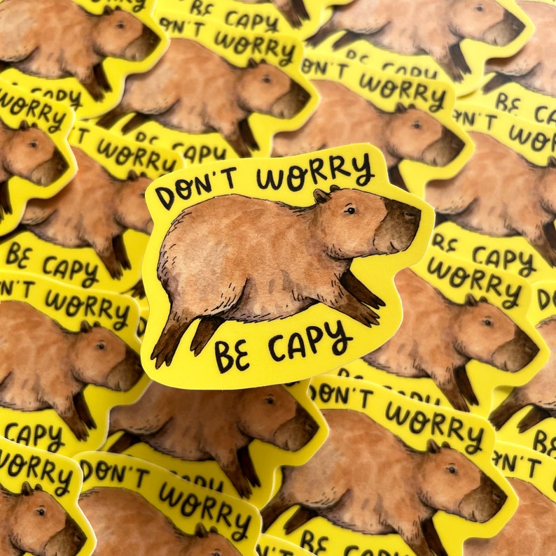 May include: A collection of yellow stickers featuring a watercolor illustration of a capybara. The stickers have the text "DON'T WORRY BE CAPY" in black. The capybara is brown with dark brown legs and a dark brown nose.