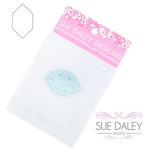 May include: A clear plastic hexagon-shaped template with six holes. The template is in a clear plastic bag with a pink label that says "Sue Daley Designs English Paper Pieces and Accessories".