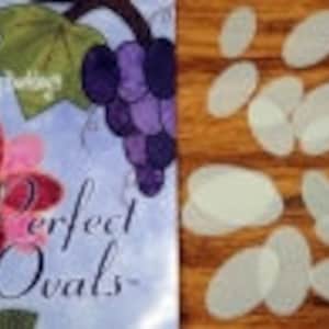 May include: A set of 10 clear plastic oval templates for quilting or crafting. The templates are on a wooden surface. The text "Perfect Ovals" is visible on a fabric background.