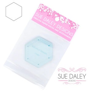 May include: A clear plastic 1-inch hexagon template for quilting, sewing, and crafting. The template is packaged in a clear plastic bag with a pink label that reads "Sue Daley Designs English Paper Pieces and Accessories".