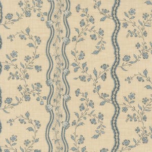 May include: Cream-colored fabric with a repeating pattern of blue floral vines and wavy blue stripes. The design features delicate blue flowers and leaves, creating a classic, elegant aesthetic. The fabric has a textured appearance.