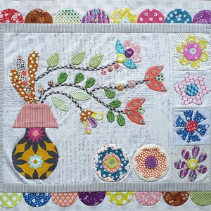 May include: A colourful patchwork quilt with a floral design. The quilt features a vase with flowers, leaves, and a variety of colourful fabrics. The quilt is surrounded by a border of scalloped fabric.