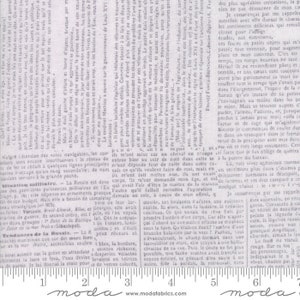 Könnte beinhalten: Eine Nahaufnahme eines grauen und weißen Stoffes mit einem sich wiederholenden Textmuster. Der Stoff hat ein Lineal mit Zollmarkierungen. Der Text auf dem Stoff ist in Französisch und größtenteils unleserlich. Der Stoff ist hellgrau mit einer dezenten Textur.