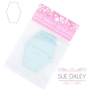 May include: A light blue plastic template shaped like a hexagon with rounded corners. The template is labeled "SUE DALEY DESIGNS COFFIN". The template is packaged in a clear plastic bag with a pink label that reads "SUE DALEY DESIGNS ENGLISH PAPER PIECES AND ACCESSORIES".