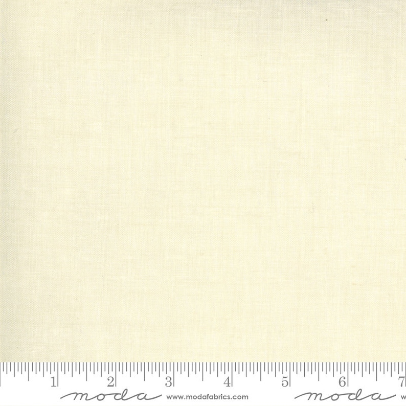 Puede incluir: Primer plano de una tela de color crema con una textura sutil. La tela se mide con una regla que dice "moda" e incluye la direcci&oacute;n del sitio web "www.modafabrics.com".