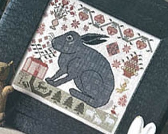 May include: A cross-stitch pattern depicting a grey rabbit holding a red and white gift box. The rabbit is surrounded by various festive elements, including snowflakes, stars, and a small Christmas tree. The pattern is framed in a dark wood frame.