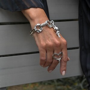 May include: A silver bracelet with a heart-shaped charm and a silver ring with a heart-shaped design.