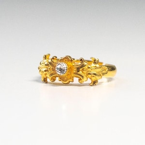 May include: A gold ring with a clear stone set in a decorative design.