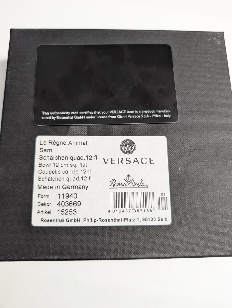 Puede incluir: Una caja negra con una etiqueta blanca con el logotipo de Versace y detalles del producto, incluyendo "Le R&egrave;gne Animal" y "Bowl 12 cm sq. flat". La caja tambi&eacute;n tiene una tarjeta de autenticidad negra.