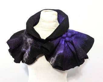 May include: A black and purple felted wool collar with a ruffled design. The collar has a large flower-shaped embellishment on the right side.