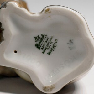 Może przedstawiać: Zbliżenie na sp&oacute;d porcelanowej figurki. Figurka jest oznaczona słowami "Germany, Kunstabteilung, Selb, Handgemalt" zielonym nadrukiem.