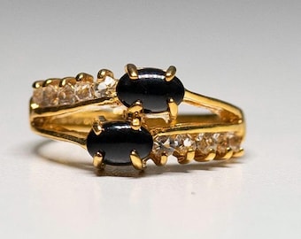 May include: A gold ring with two black oval stones and a row of clear stones.