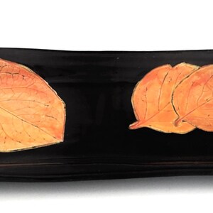 Bandeja rectangular negra y caqui con hojas.