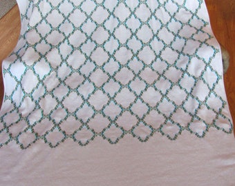 May include: White throw blanket with a geometric pattern of teal and brown squares. The blanket has a fringe border.