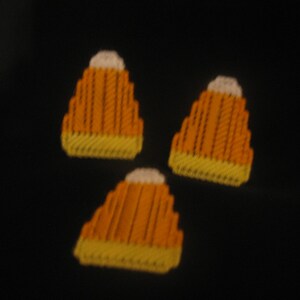 May include: Three orange and white felt candy corn ornaments. The candy corn is a traditional Halloween decoration.