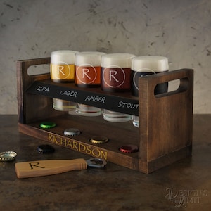 Pode incluir: Um suporte de voo de cerveja de madeira com seis copos, cada um com um r&oacute;tulo de estilo de cerveja diferente: IPA, Lager, Amber, Stout. Os copos s&atilde;o gravados com a letra "R". O suporte tem uma superf&iacute;cie de quadro-negro com o nome "RICHARDSON" escrito em letras douradas. Um abridor de garrafas de madeira com a letra "R" est&aacute; inclu&iacute;do.