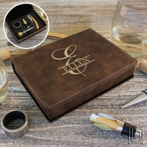 May include: A brown faux leather box with a gold monogram of the letter "E" and the name "ELLEN" engraved on the top. The box contains a wine opener set.