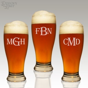May include: Three clear glass beer mugs with a frosted rim and a wide base. Each mug is filled with a dark amber beer and has a white monogram etched on the front. The monograms are "MGH", "FBN", and "CMD".