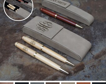 May include: Two wooden pens with gold accents and engraved initials in a beige leather pen case. The case has a flap with the name "BRIAN SMITH" engraved on it.